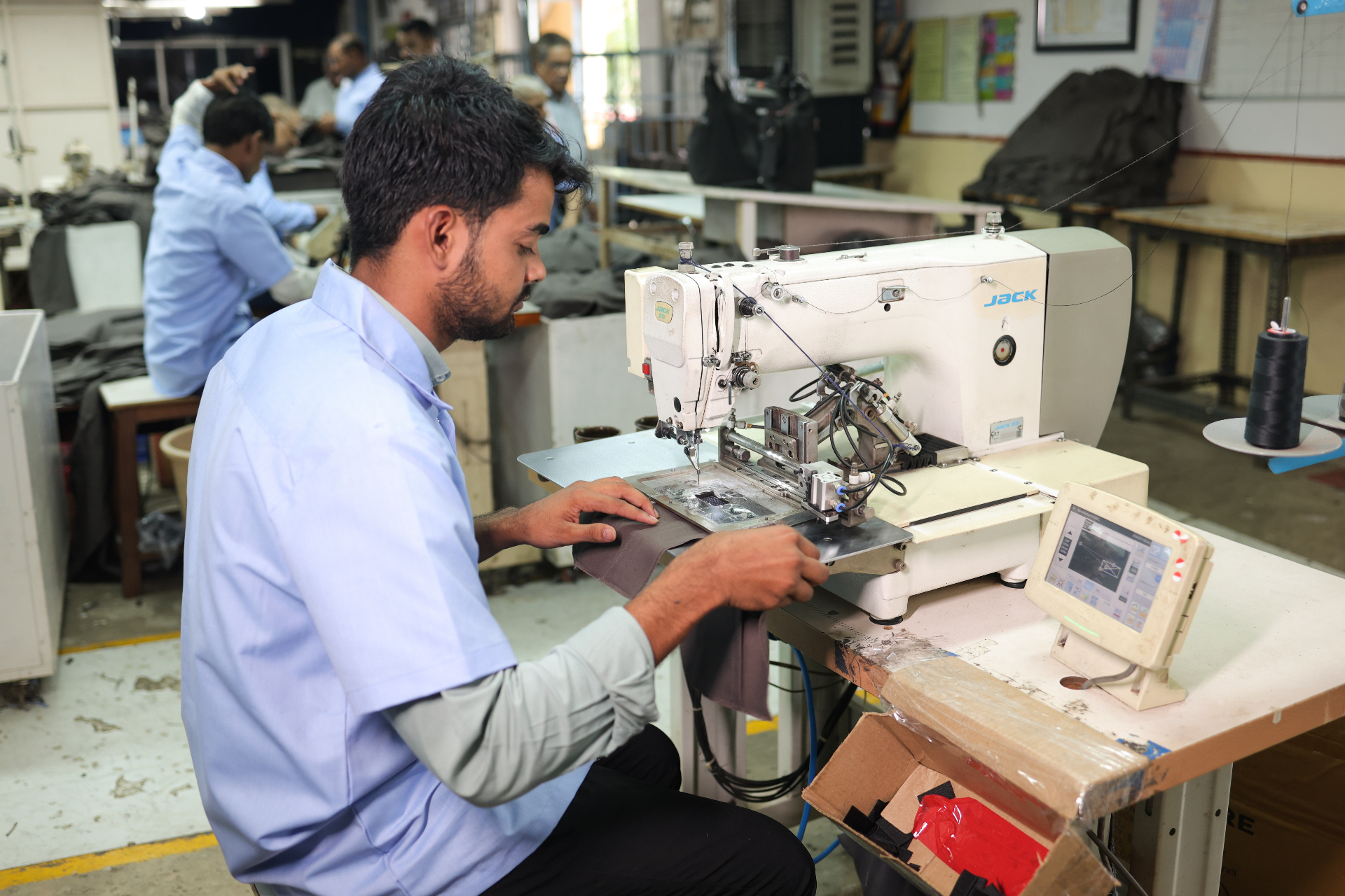 Tailor operating computerized sewing machine on the production floor